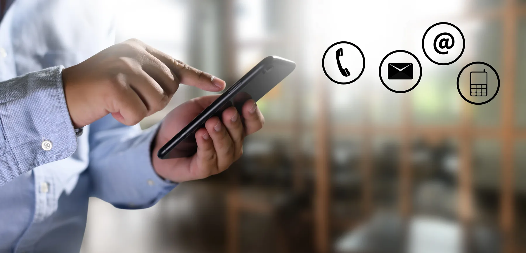 A person in a blue shirt using a smartphone, with phone, envelope and at-sign icons alongside.